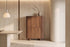 The Menton Highboard in walnut against a travertine wall beside an alabaster pendant