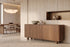 The Menton Sideboard in walnut in a travertine dining room beneath an alabaster sphere chandelier