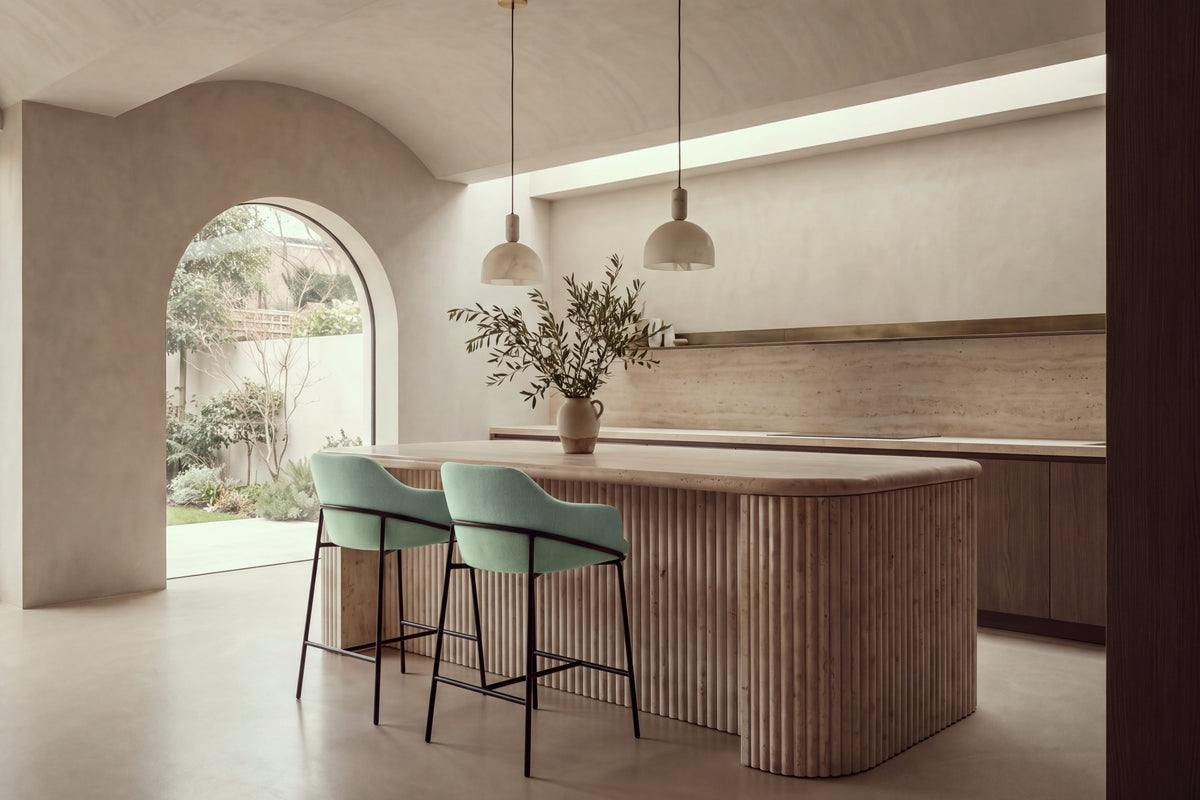 Two Moneglia Counter Stools in mint green with black legs at a fluted travertine kitchen island
