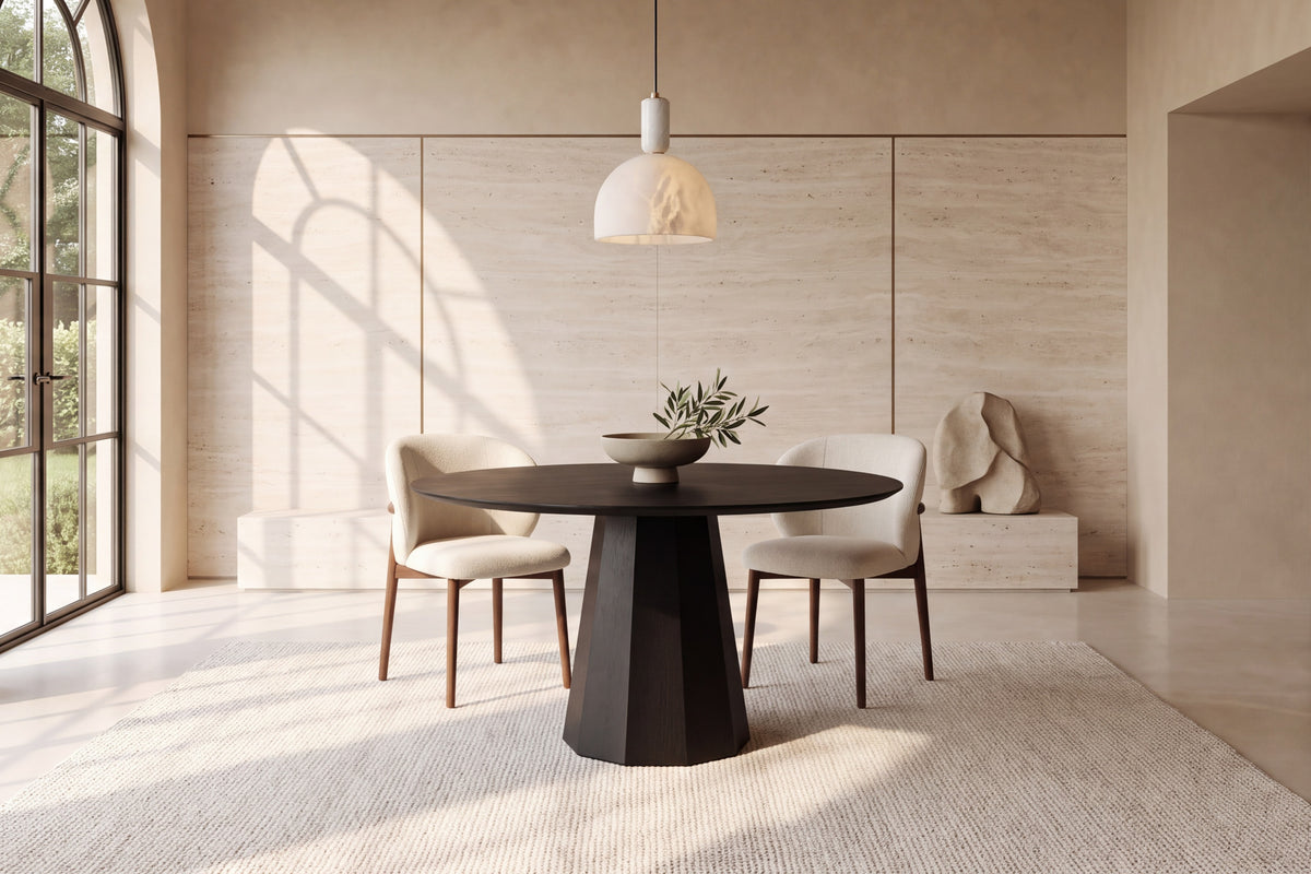 The Monza Round Dining Table in black with Norcia chairs beneath a Cupola alabaster pendant against a travertine slab wall