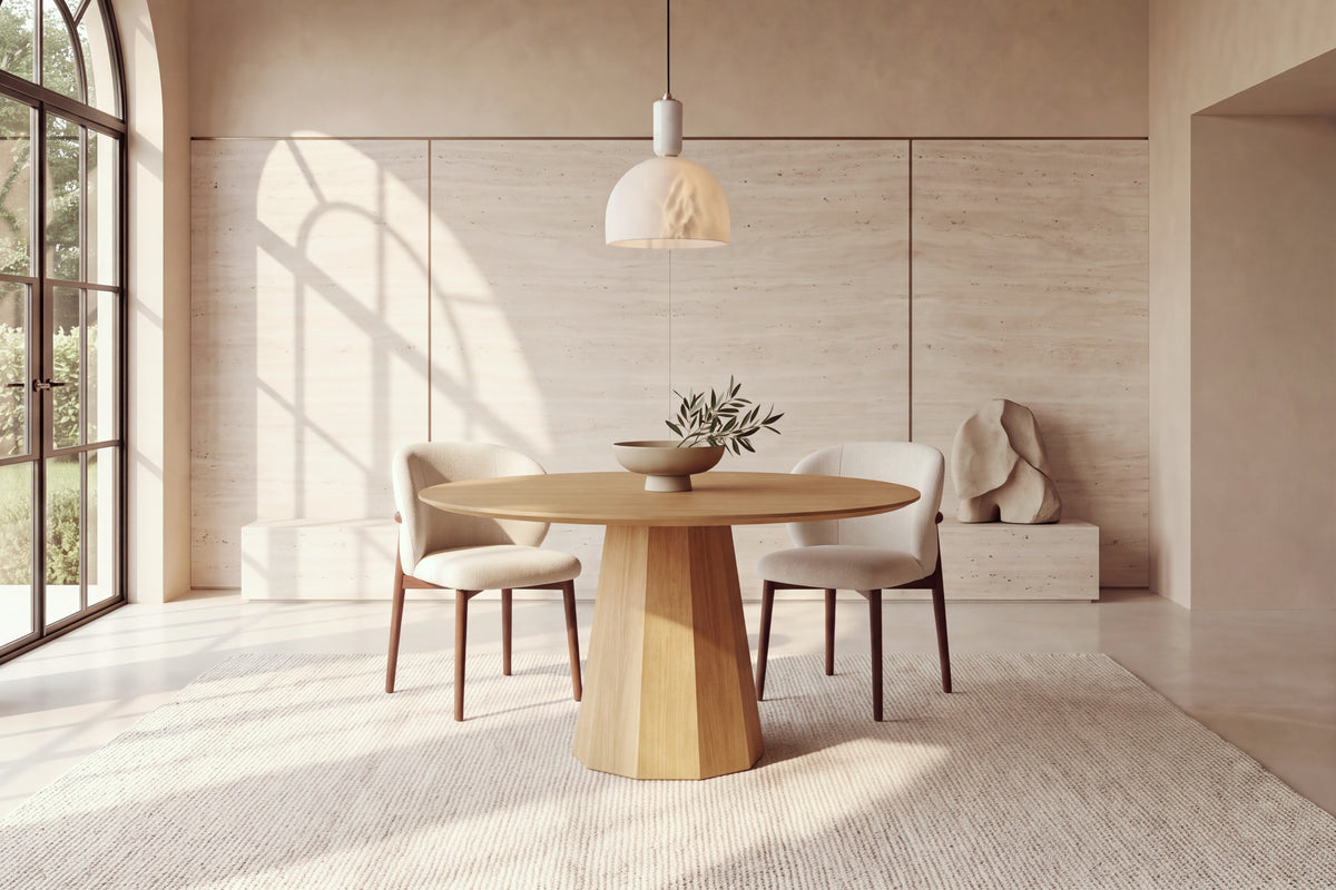 The Monza Round Dining Table in oak with Norcia chairs beneath a Cupola alabaster pendant against a travertine slab wall