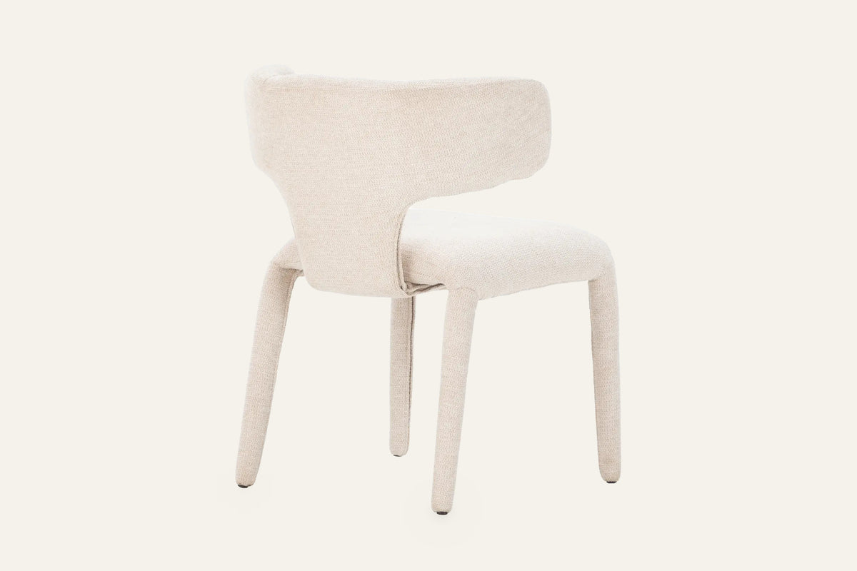 The Nemi Dining Chair in beige, fully upholstered curved dining chair, studio view