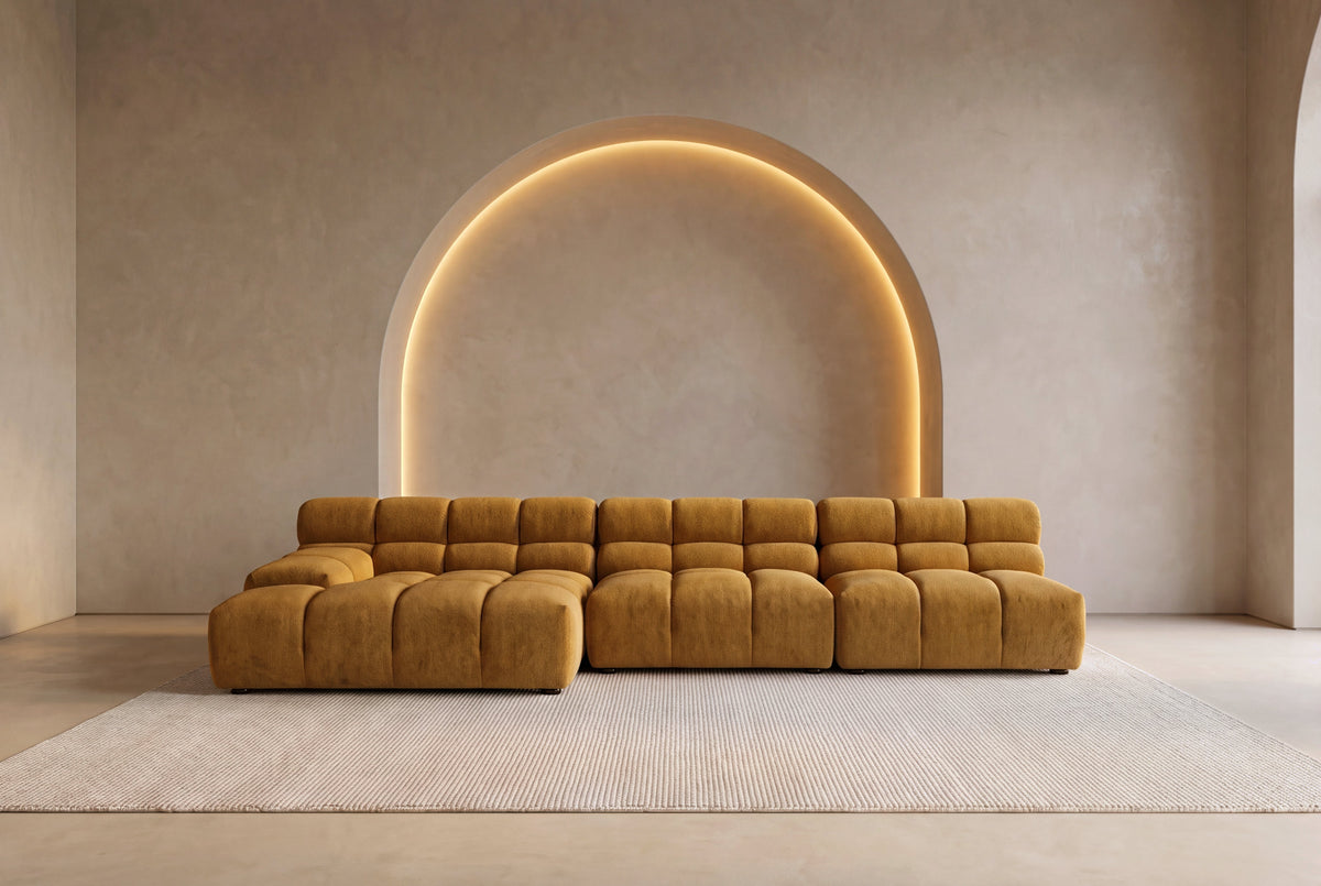The Parma Tufted Modular Sofa in ochre in a grand plaster room with a glowing arched niche
