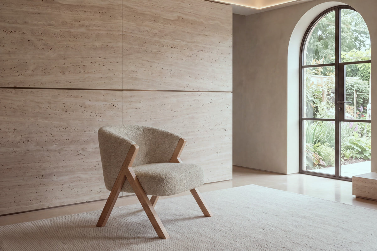 The Pizzo armchair in beige boucle against a travertine wall