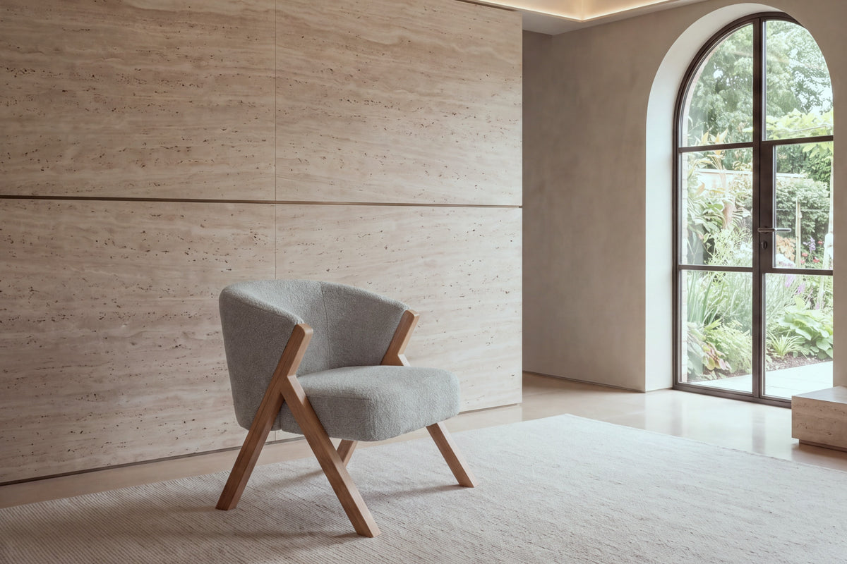 The Pizzo armchair in light grey boucle against a travertine wall
