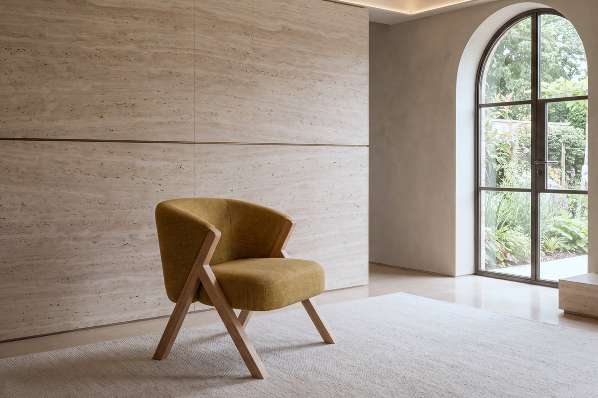 The Pizzo armchair in mustard boucle on a wool rug against a travertine wall
