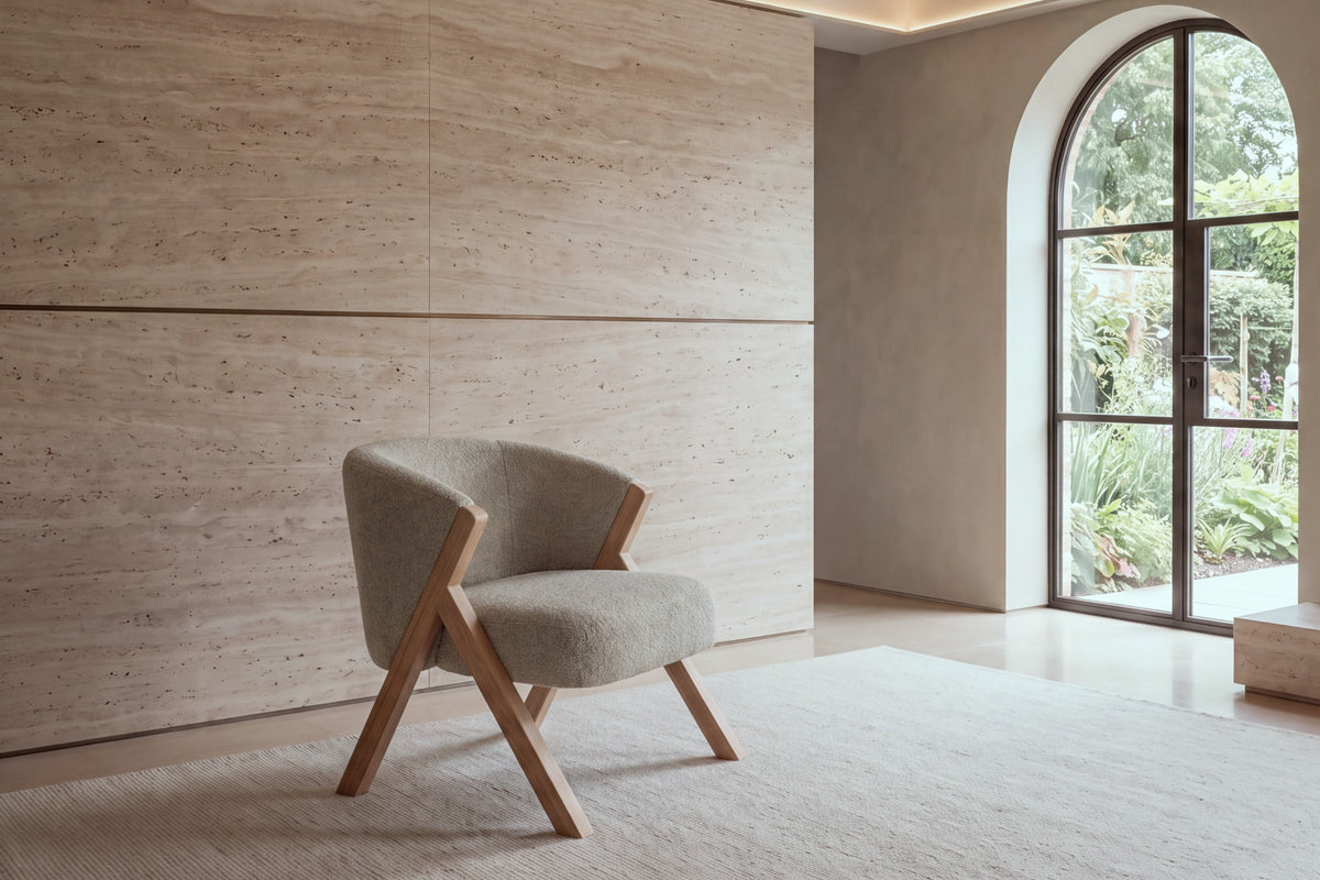 The Pizzo armchair in taupe boucle against a travertine wall
