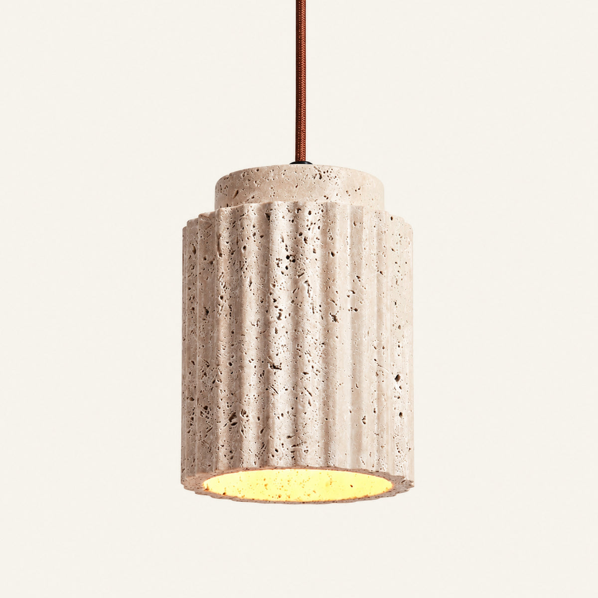 The Plissé travertine pendant light, a fluted cream stone cylinder hanging from a brown cable