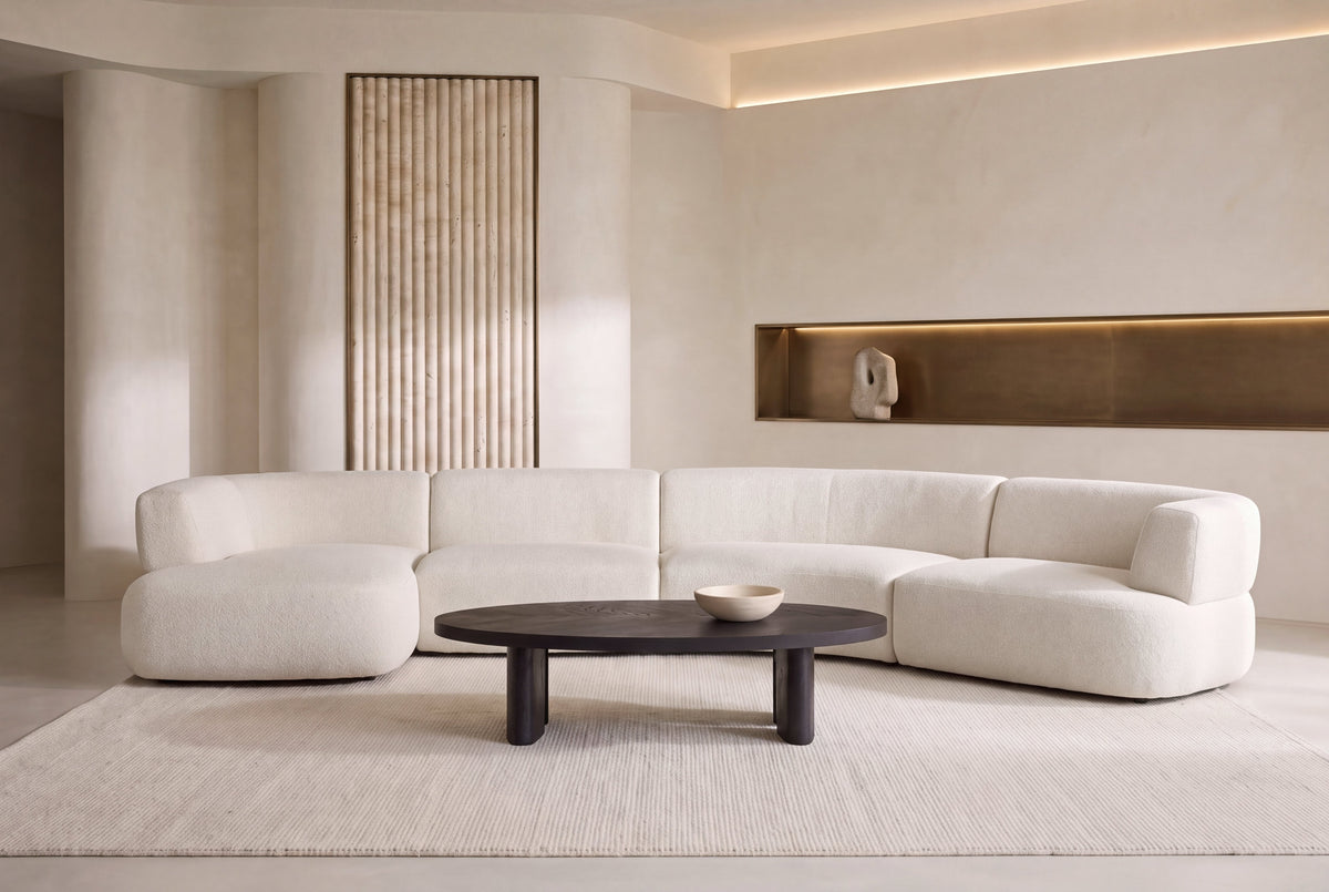 The Ravenna Curved Modular Sofa in ivory with an oval travertine coffee table in a tall plaster living room
