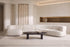 The Ravenna Curved Modular Sofa in ivory with an oval travertine coffee table in a tall plaster living room