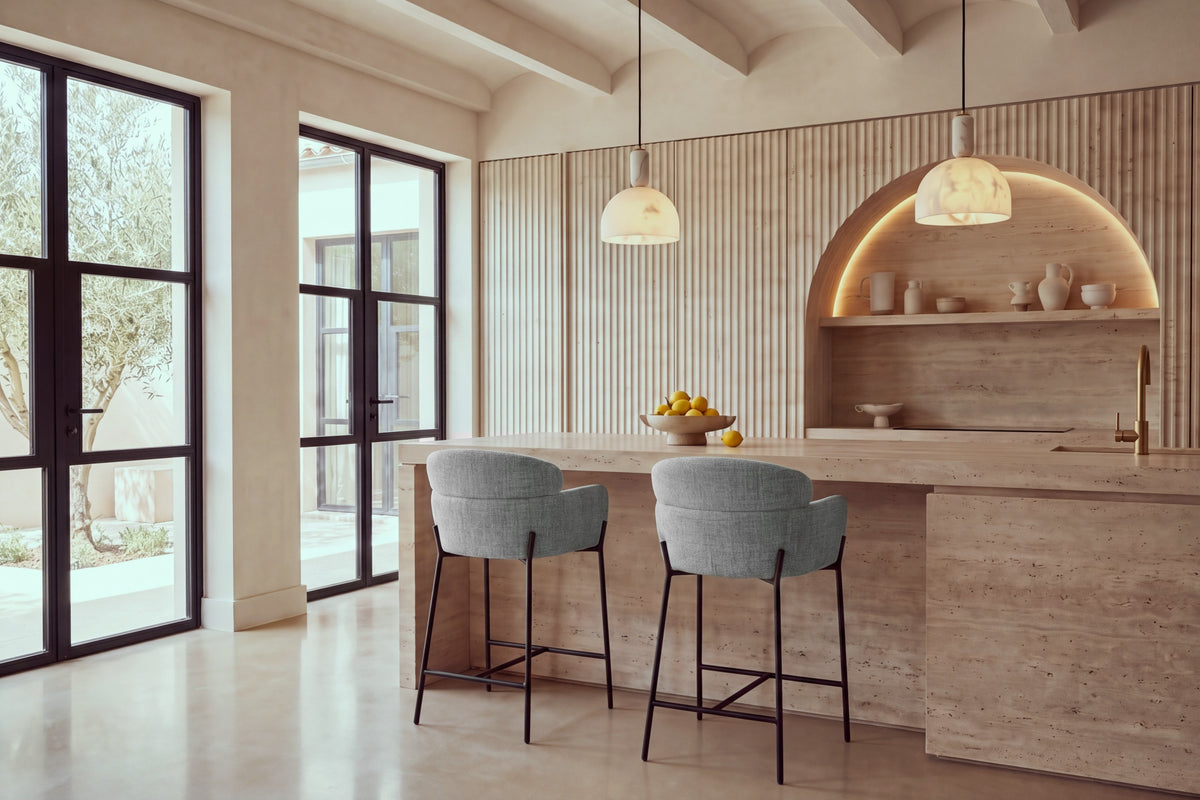 Two Recco Counter Stools in grey at a travertine kitchen island beneath alabaster pendants