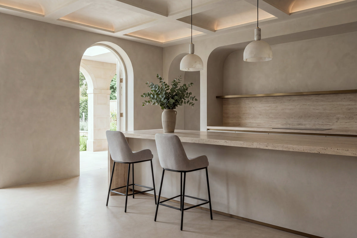 Two Riomaggiore Counter Stools in light grey at a kitchen island beneath alabaster pendants and a coffered ceiling