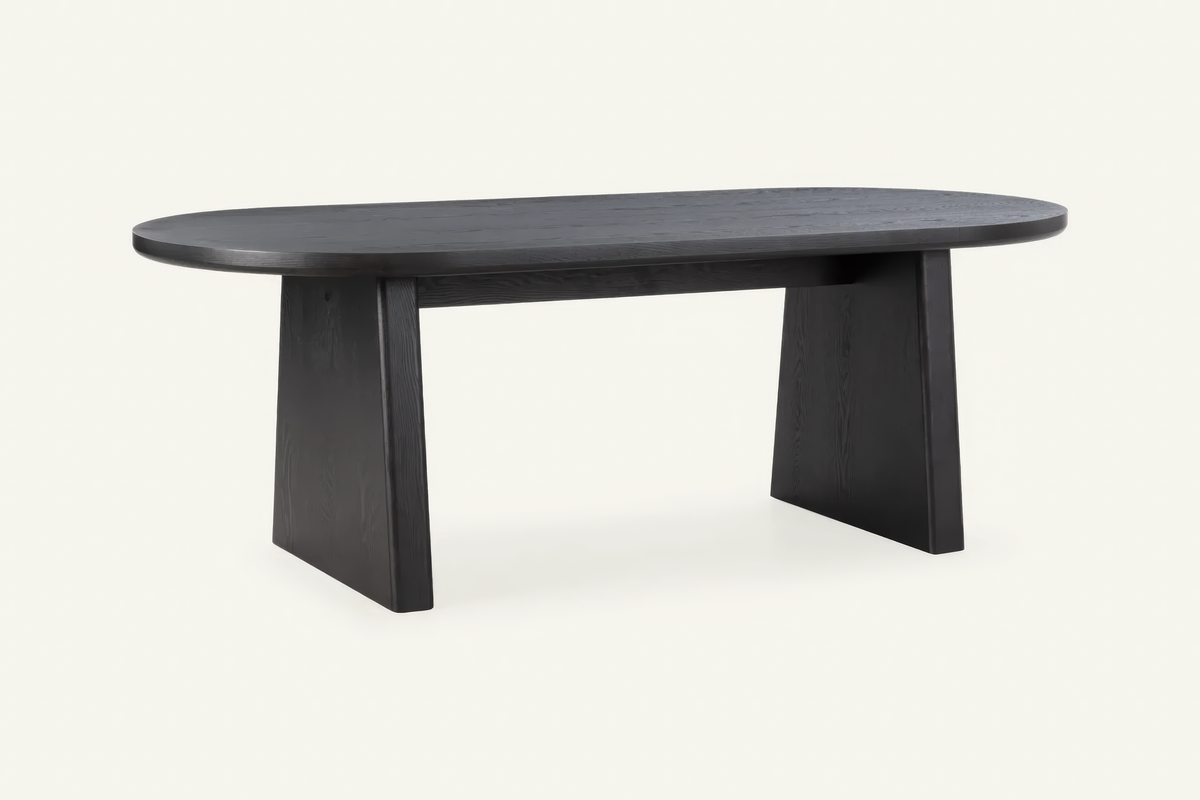 The Sutri Oval Dining Table in black, oval dining table on panel legs, studio view