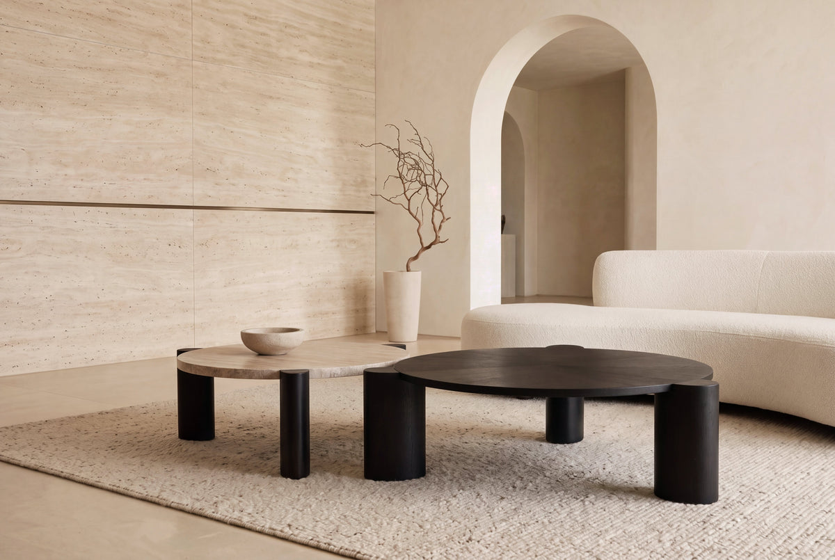 The Ischia Coffee Table Set in black oak and travertine in a living room with a travertine wall and arched opening