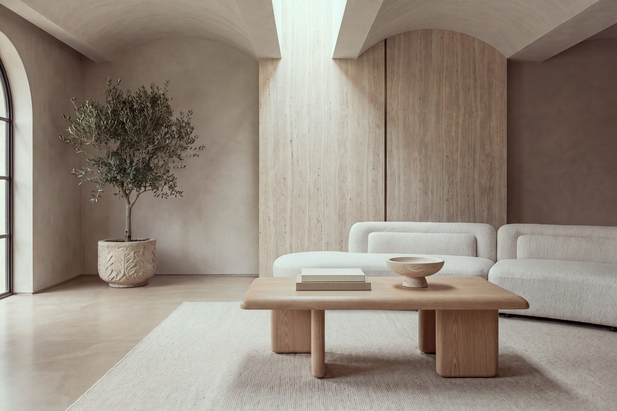 The Tremezzo Coffee Table in oak in a barrel-vaulted living room with a travertine wall and an ivory boucle sofa