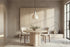 The Ortigia Travertine Finish Round Dining Table with Norcia chairs and a Cupola alabaster pendant in a travertine-walled dining room