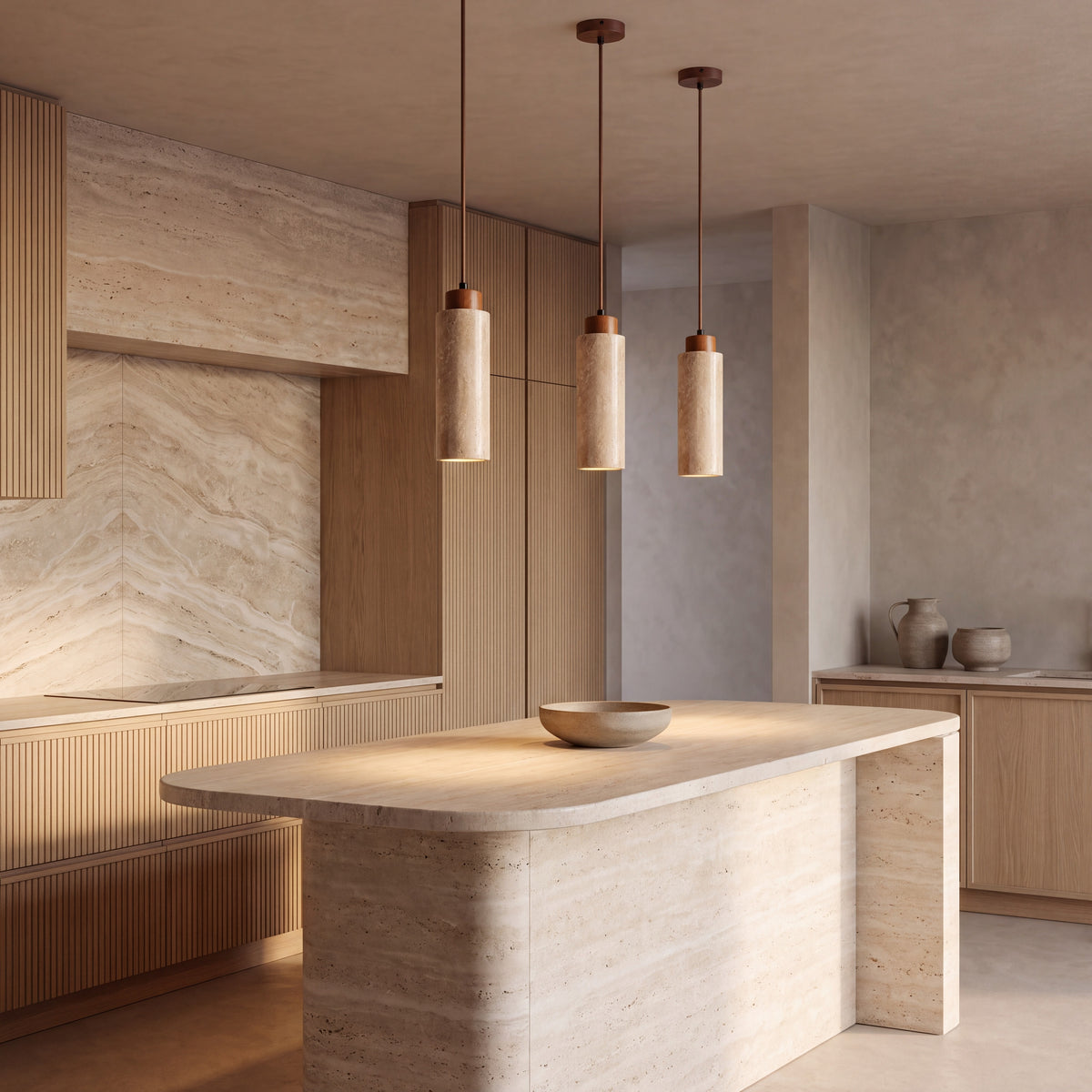 Three Pistillo travertine pendant lights above a travertine kitchen island