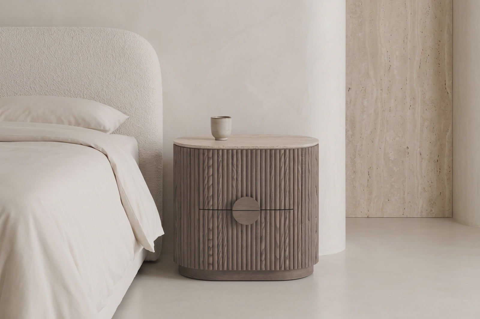 Spello fluted travertine bedside table beside a boucle bed