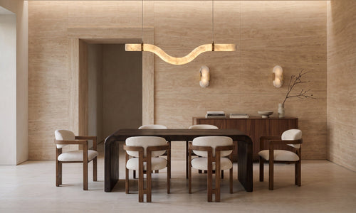 Travertine dining room with a walnut table and boucle armchairs beneath an alabaster pendant, sunlight moving across the walls