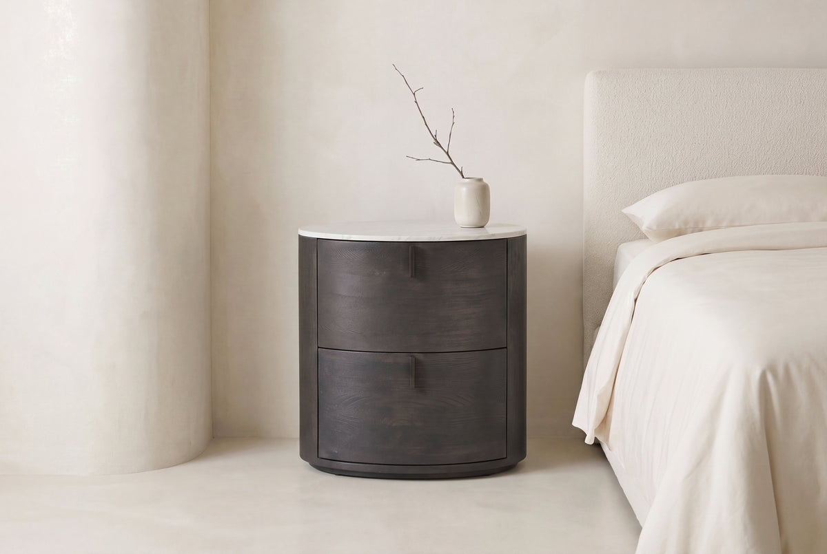 The Bolsena Oval Stone Bedside Table in a bedroom setting