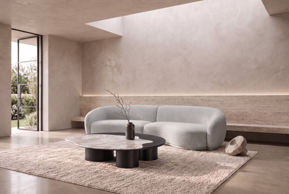The Caldera Coffee Table with The Elira Sofa in a plaster room with a skylight and travertine bench