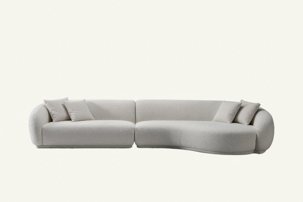 The Elira Sofa in ivory boucle with matching cushions and a curved chaise, front view