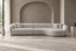 The Elira Sofa in ivory boucle with a curved chaise, in a mushroom plaster living room with an arched niche