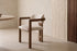 The Gubbio Dining Armchair beside a travertine dining table