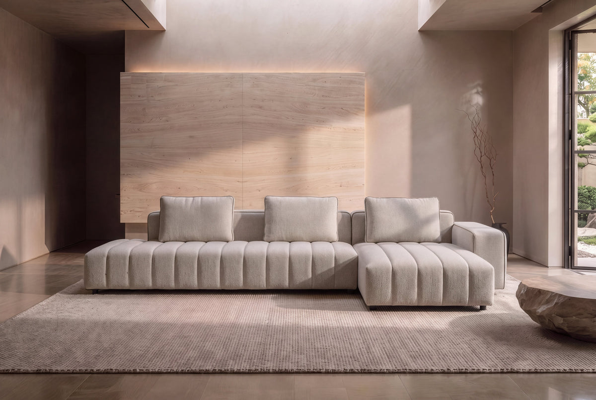 The Lucca Chaise Sofa in oatmeal textured weave in a plaster-walled living room with a garden view