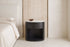 The Ostuni Black Oak and Stone Bedside Table in a bedroom setting