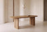 The Radda Oval Dining Table in light oak in a plaster and travertine dining room