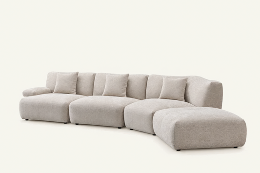The Solaro Modular Sofa in oatmeal chenille with matching cushions, curved configuration with ottoman, angled view