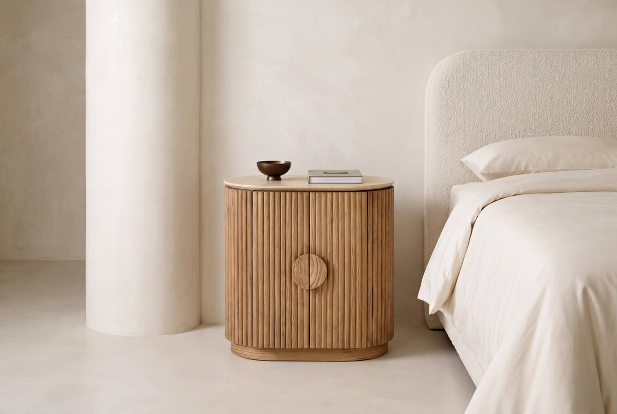 The Spello Fluted Travertine Bedside Cabinet in a bedroom setting