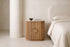 The Spello Fluted Travertine Bedside Cabinet in a bedroom setting