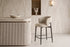The Trevi Bar Stool at a fluted travertine kitchen island