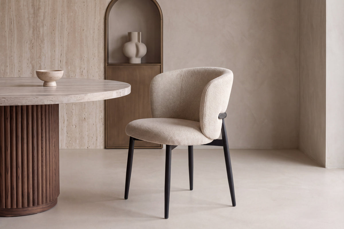 The Trevi Dining Chair beside a round travertine dining table