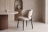 The Trevi Dining Chair beside a round travertine dining table
